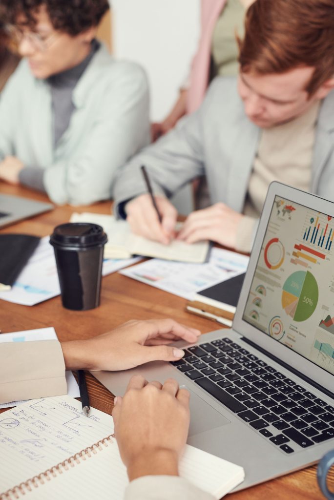Professionals working together in an office setting with charts on a laptop for data analysis.